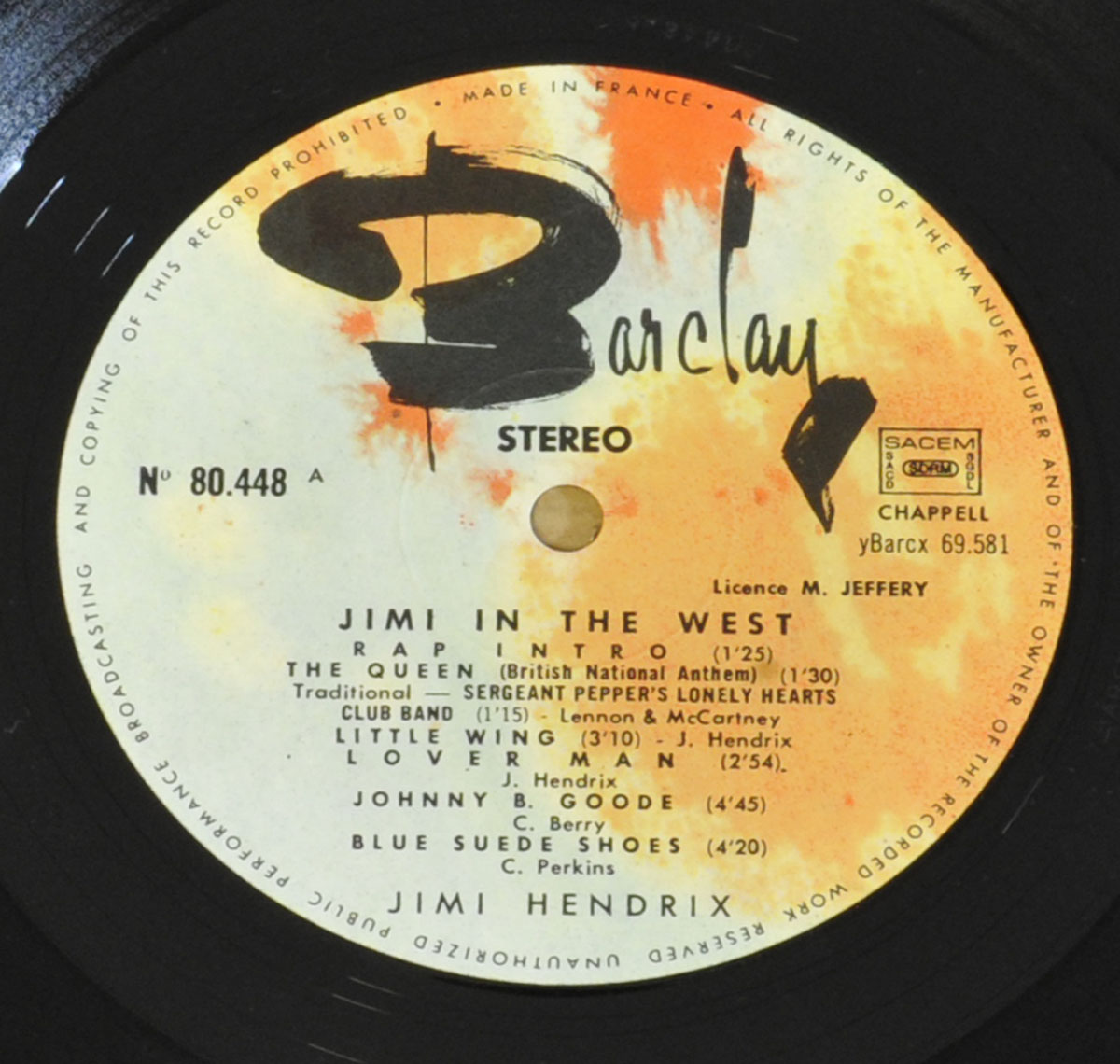 Close-up of the record label from 'Jimi in the West,' released under the Barclay label. The label has an artistic black and orange design with track listings for Side A, featuring songs such as 'Little Wing,' 'Johnny B. Goode,' and 'Blue Suede Shoes.' Notably, the album title on the record label differs from the album cover, where it is titled 'Hendrix in the West.' The label also includes the catalog number (80.448 A), licensing details, and production credits.